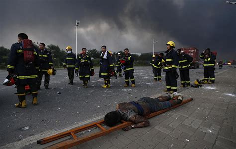 Firemen stand beside a body after a huge explosion rocked the port city ...