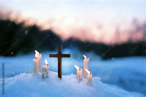 Christian cross and candles on snow, evening winter natural blurred background. Advent time ...