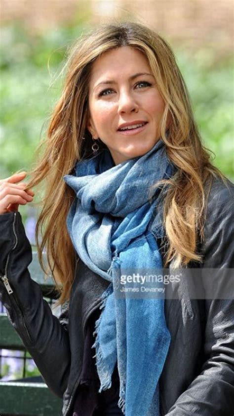 a woman in black jacket and blue scarf sitting on a bench