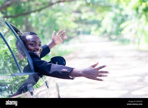 African business man driving and smiling while sitting in a car with ...