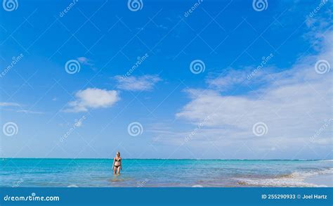 Blonde Woman in Black Bikini in Calm Water at Beach Against Blue Sky ...