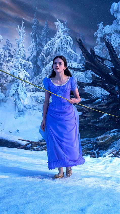 a woman in a blue dress is walking through the snow while holding a stick with her hand