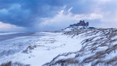 Bamburgh Castle and sand dunes after snowfall in Northumberland (© Ross ...