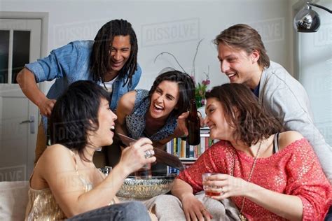 Friends laughing together in living room - Stock Photo - Dissolve