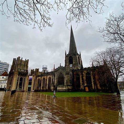 an old building with a steeple in the middle of it on a rainy day