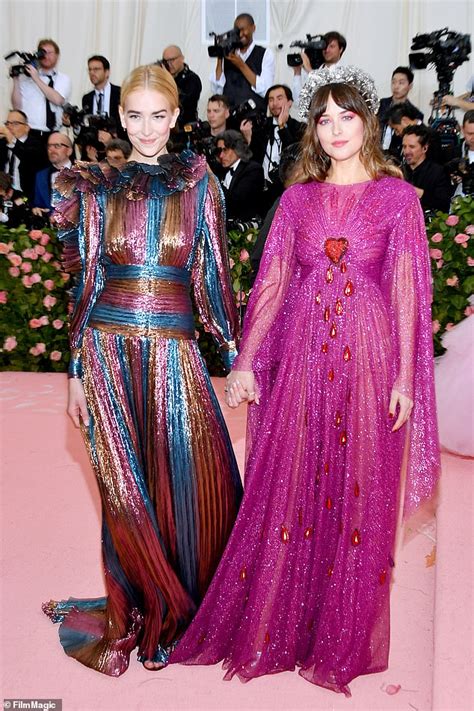 Dakota Johnson, 29, holds hands with younger sister Grace, 19, as they attend the Met Gala ...