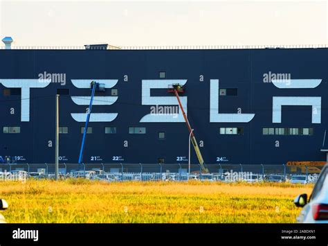 Construction workers put up the "Tesla" logo on the outside wall of Tesla Gigafactory under ...