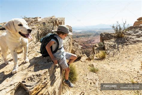 Young boy hiking with his dog on Chimney Rock trail, through a protected canyon landscape ...