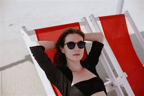 "Woman Relaxing At The Beach In Chaise Lounge" by Stocksy Contributor "Amor Burakova" - Stocksy