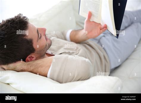 Man in sofa reading book Stock Photo - Alamy