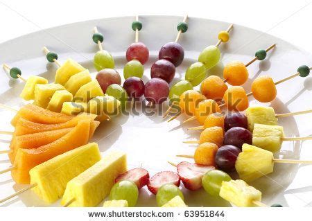 fruit skewers arranged in a circle on a plate