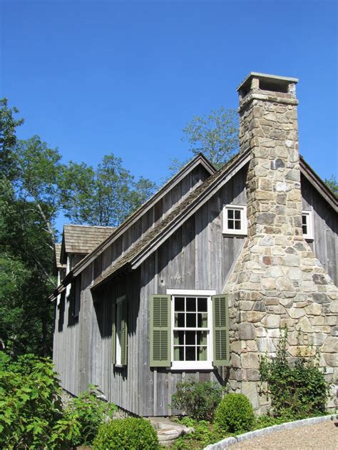 an old stone house with green shutters on the windows and a chimney in front