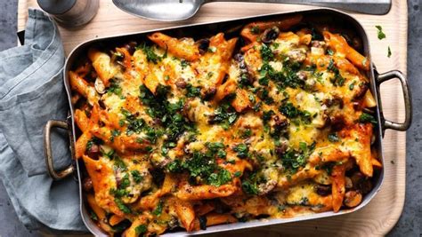 a casserole dish with cheese and vegetables in it on a wooden platter