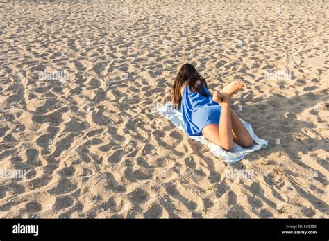 Rear view of pretty girl lying on sandy beach on hot summer Stock Photo - Alamy