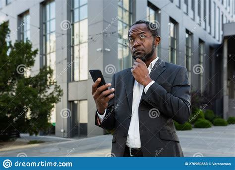 A Serious African American Businessman in a Business Suit is Standing on the Street Near a ...