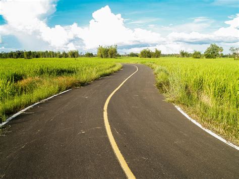 Paved Road in Between Green Grass Field · Free Stock Photo