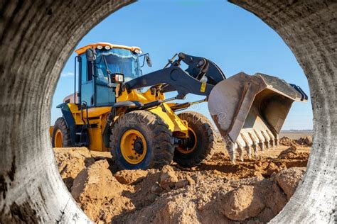 Bulldozer or Loader Moves the Earth at the Construction Site Against ...