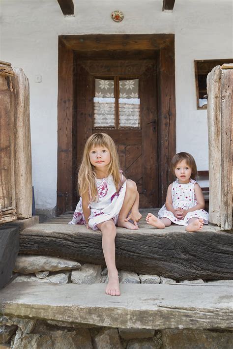 "Little Girls Sitting Down On Stairs In Front Of Traditional Home" by Stocksy Contributor "Ibex ...