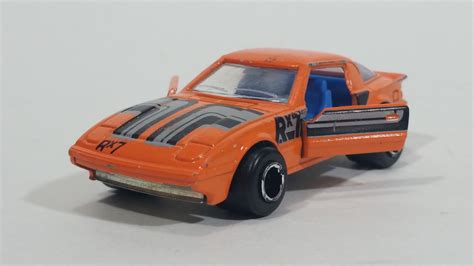 an orange toy car with black stripes on the front and back sides, sitting on a white surface