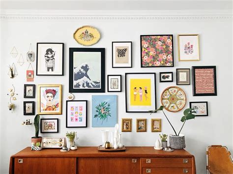 gallery wall- an assortment of art and objects hang on a wall above a sideboard Gallery Wall ...