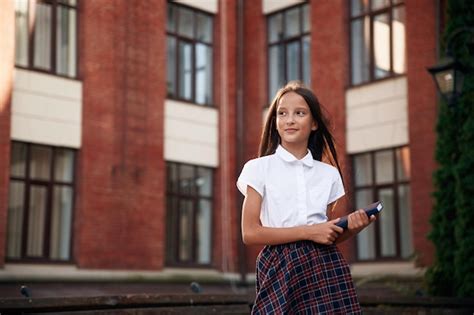 Premium Photo | Orange colored building school girl in uniform is outdoors