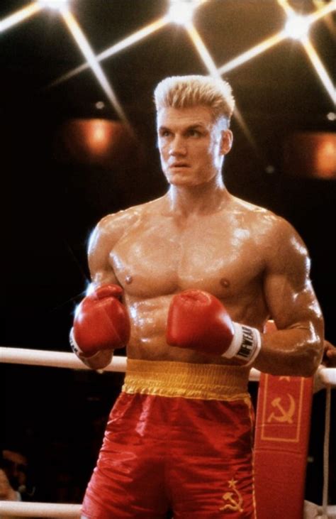 a man in red boxing shorts standing next to a punching ring with his hands on his hips