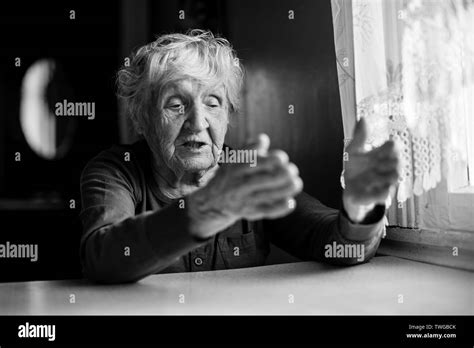 The old lady is sitting talking gesticulating at the kitchen table. Black and white photo Stock ...