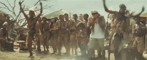 a group of men standing around each other in front of trees and people with their hands up