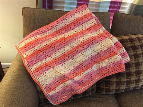 Crochet blanket done with sweet roll yarn in the color peaches and cream(?). Diamond pattern.