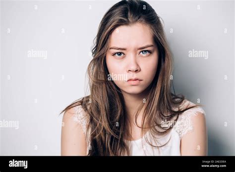 Close up isolated portrait of young annoyed angry woman. Young female in white T-shirt. Negative ...