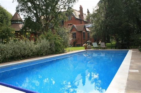 The bright blue mosaic of this large family size pool contrasts beautifully with the traditional ...