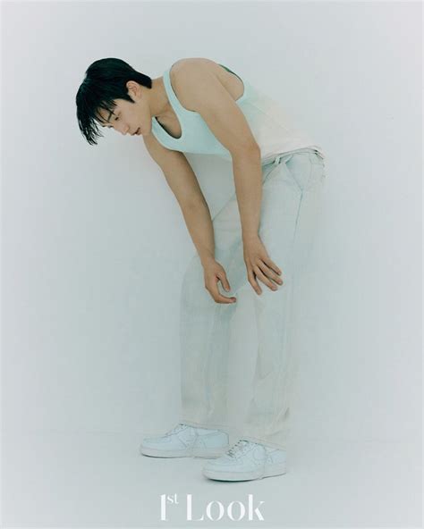 a woman in white shirt and pants leaning against wall with her hands on her knees