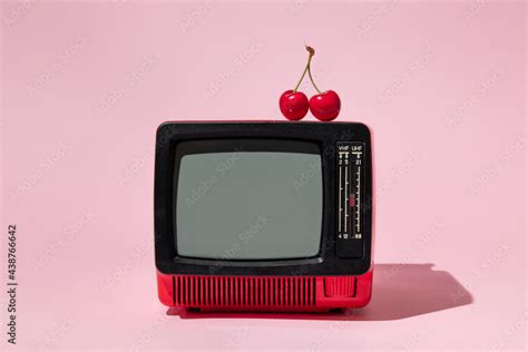 Creative layout with old tv and bright red cherry on pastel pink ...