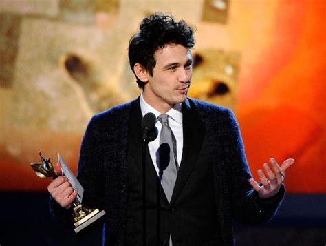 a man in a suit and tie holding an award for best performance by an actor