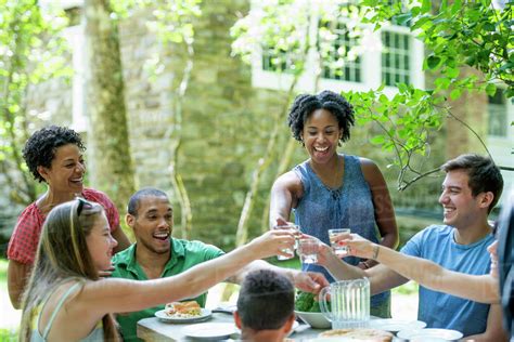 A family gathering, men women and children around a table in a garden ...