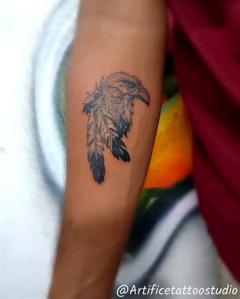 a person with a tattoo on their arm that has a bird and feathers on it