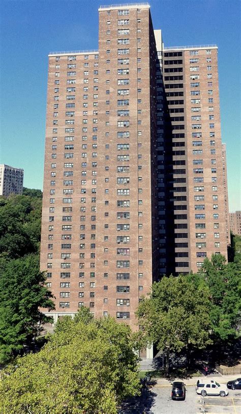 an apartment building with cars parked in the parking lot next to it and several trees