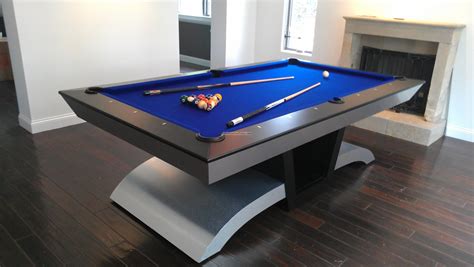 a pool table in the middle of a living room with a fireplace and hardwood floors