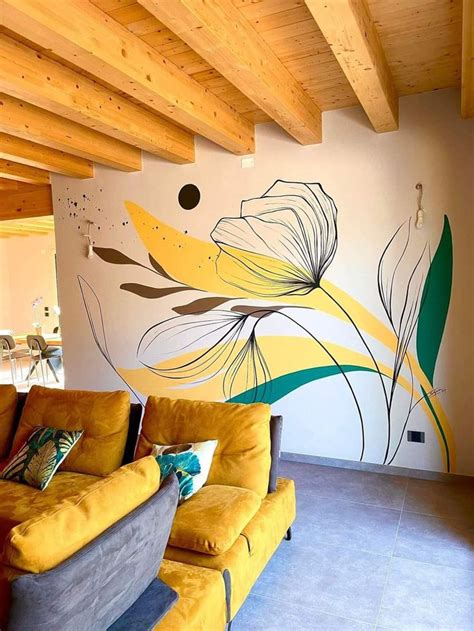 a yellow couch sitting in front of a painting on the wall next to a wooden ceiling