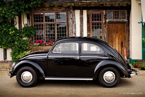 an old black car parked in front of a building with flowers growing on the side