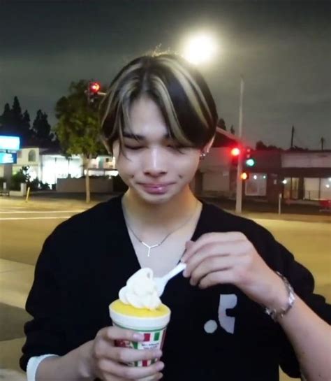 a young man is eating an ice cream sundae at night in front of traffic ...