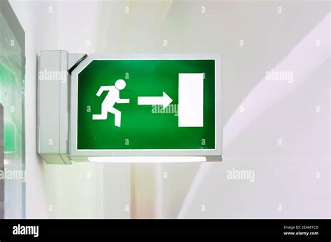 Illuminated green emergency exit sign Stock Photo - Alamy