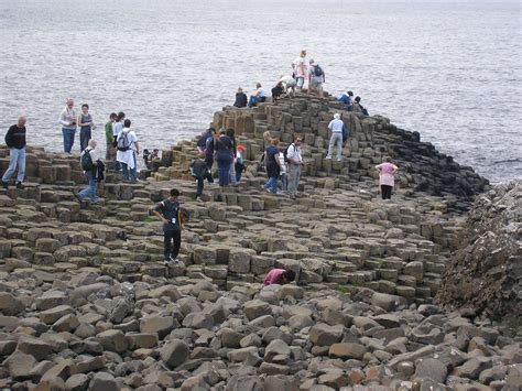 many people are standing on the rocks by the water and one person is taking pictures