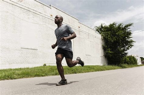 Black man running on city street stock photo