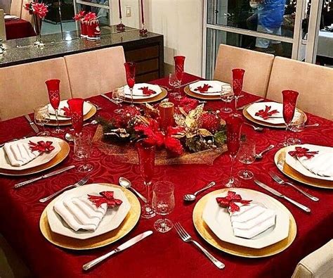 a dining room table set for christmas with red and white plates, silverware and napkins