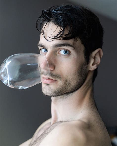 a man with no shirt holding a water bottle in his mouth