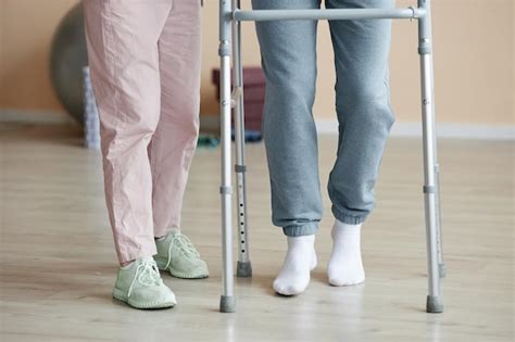 Premium Photo | Closeup of patient learning to walk with walker together with doctor helping him