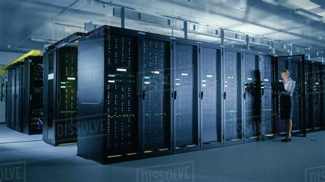 In Data Center: Female IT Technician Stands before Open Server Rack Cabinet, Uses Laptop ...