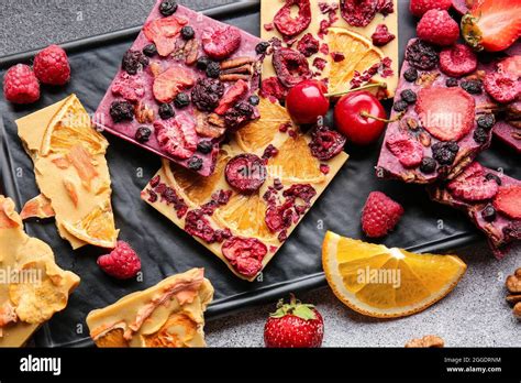 Handmade chocolate bars with fruits, berries and nuts on grey ...