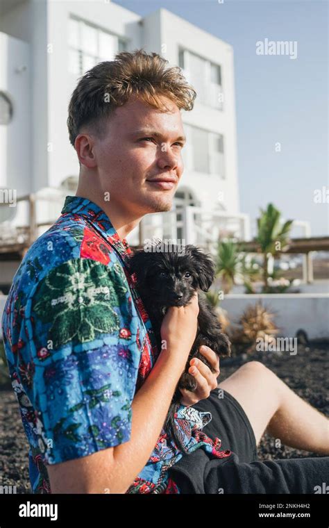 Young man sitting with cute dog in front yard Stock Photo - Alamy